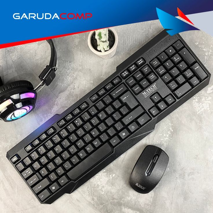 M-TECH wireless keyboard and mouse combo black on gray surface with RGB headphones in background