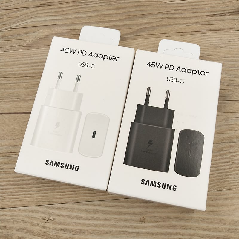Samsung 45W PD USB-C adapter white and black original retail boxes side by side on wooden surface
