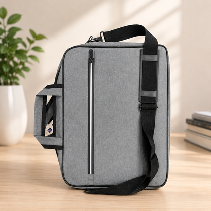 Premium slim laptop shoulder bag gray structured briefcase style angle view on wooden desk with plant and books showing front zip pocket and side mesh pocket