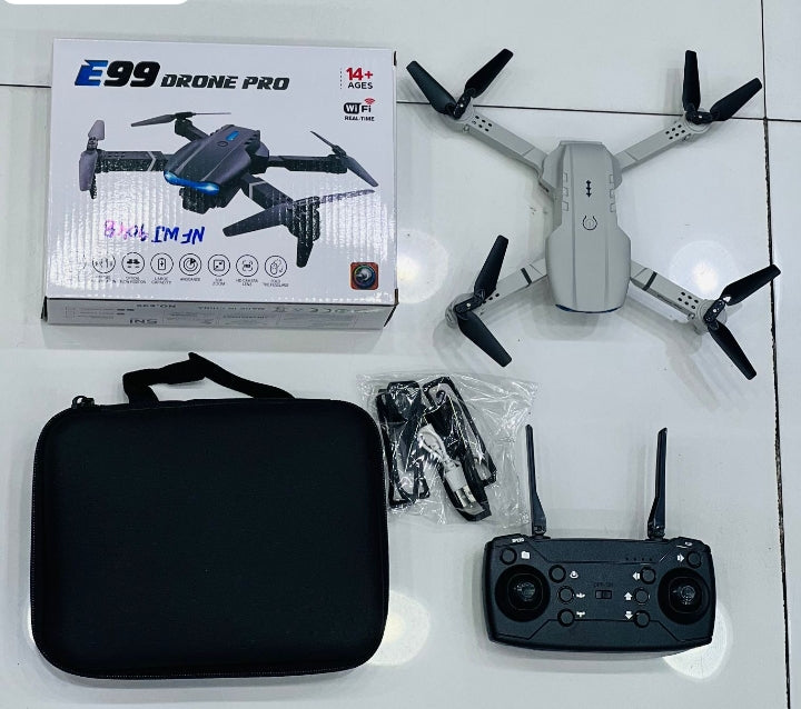 E99 Drone Pro gray unboxed showing drone, remote controller, carrying case, spare propellers and original box on white floor
