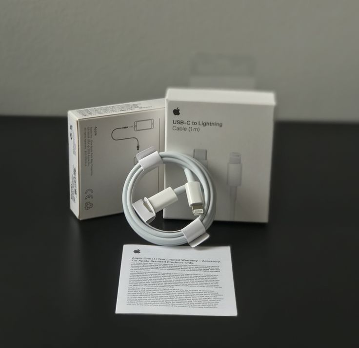 Apple USB-C to Lightning Cable 1m unboxed with original white Apple box and warranty card on dark surface
